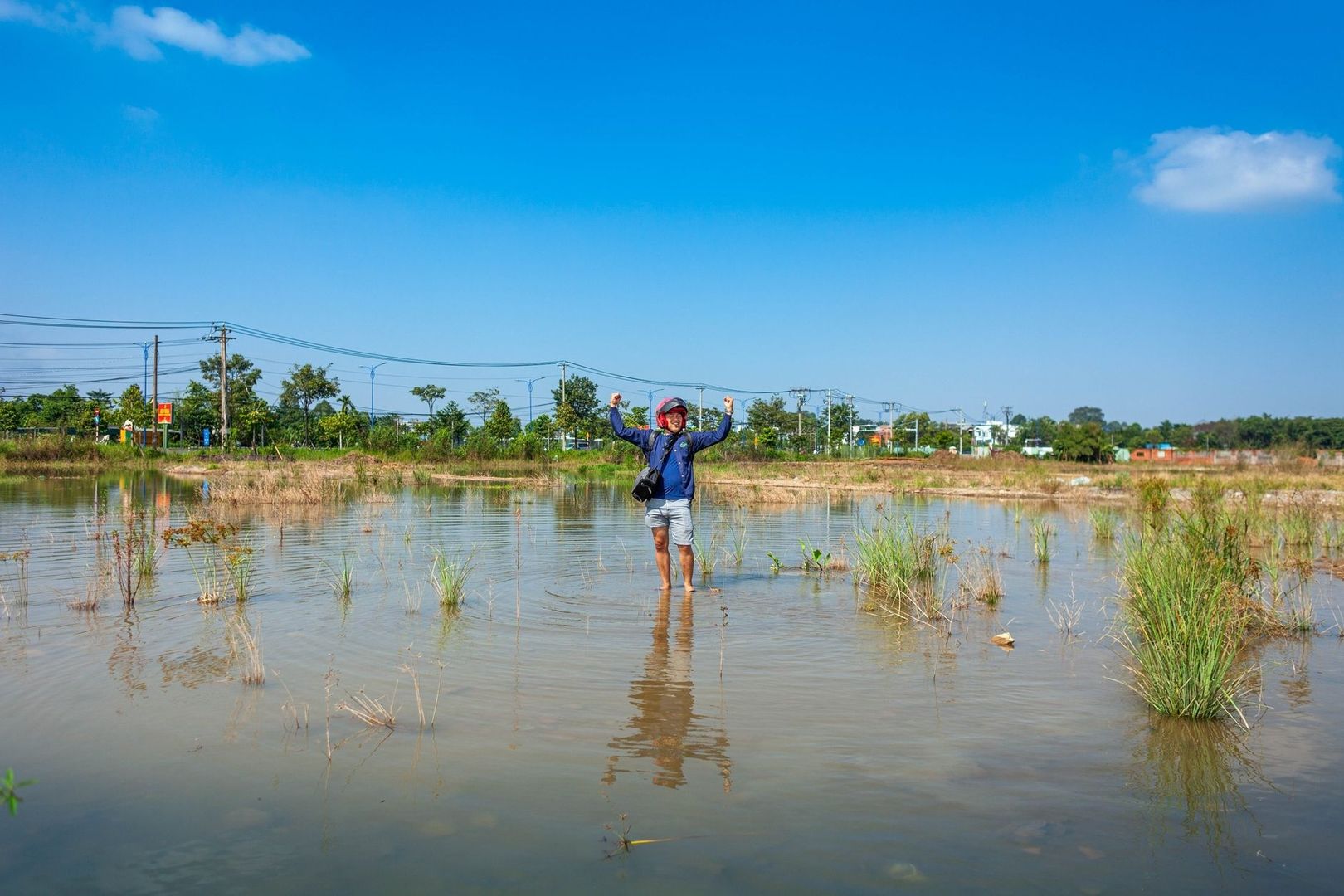 Un homme debout dans une prairie inondée, sous un ciel bleu